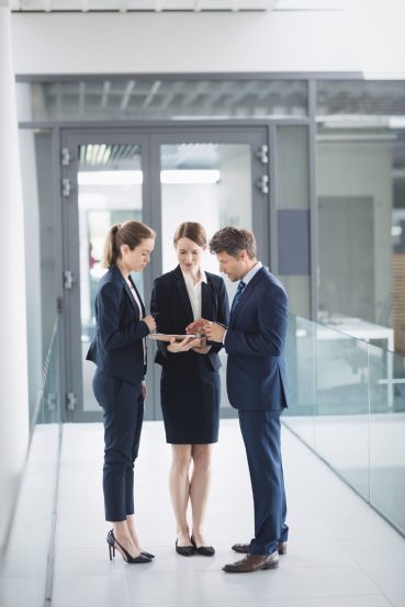 Businessman and colleague discussing over digital tablet inside office building